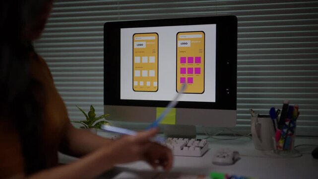 Creative web developer working on a user interface for a new mobile phone application, organizing layout and wireframe elements on a computer