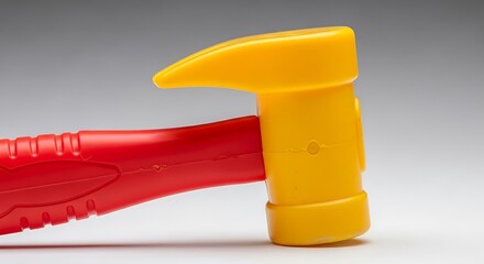 Vivid red and yellow plastic toy hammer contrasting against soft backdrop