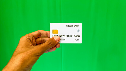 Close up view of white credit card holding by male hand isolated on green background. Man, men....