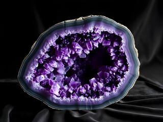 A large purple crystal is sitting on a black cloth