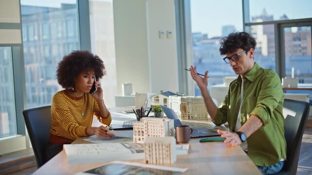 Frustrated constructors talking mobile phone in office. Mixed-race architects