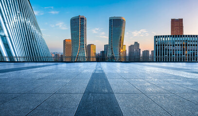 Empty square floor and modern city skyline with office buildings at sunrise in Hangzhou
