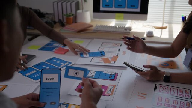 Creative team of designers brainstorming and planning the user interface for a new mobile application, collaborating on wireframe prototypes