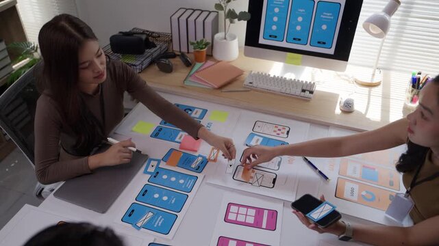 Two talented female app developers brainstorming and working together on a user interface design project for a new mobile application