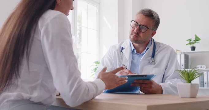 Doctor or nurse offers advice and support to a female patient during a hospital visit. Medical professional provides healthcare and aid in a clinical office, ensuring the patient receives proper care.
