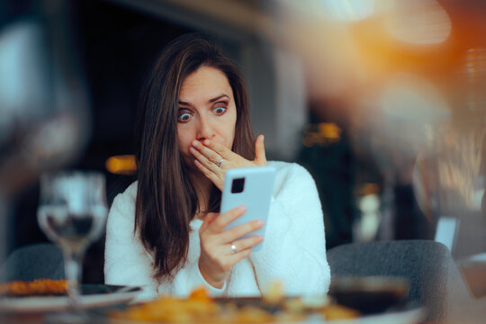 Surprised Woman Reading a Text Message in a Restaurant. Person feeling anxious because of the negative shocking online news - Powered by Adobe
