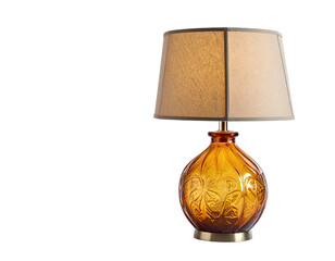 A table lamp with a patterned amber base and beige lampshade, on black background