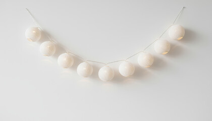 Decorative string lights with white spherical lanterns are elegantly arranged against a minimalistic background, creating a warm and inviting atmosphere for festive occasions