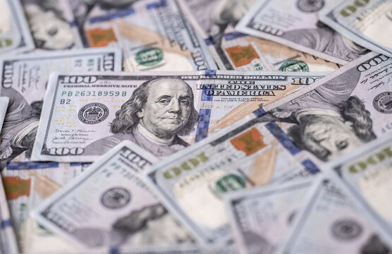 Money background with dollar bills. Texture of US dollars. 100 USD banknotes in focus. American hundred-dollars notes spread on a table. Pattern of US dollars for finance concept. Dollars currency.