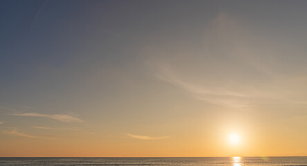Sunset sky clouds over sea water background in evening with orange, blue sun light, Horizon sea ocean sunrise sky landscape nature backgrounds and gold sun down in golden hour summer season, Dusk sky