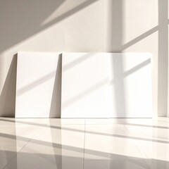 Blank canvases lean against a white wall, sunlight creates shadows
