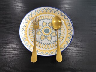 A beautifully decorated rice plate, along with a spoon.