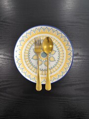 A beautifully decorated rice plate, along with a spoon.