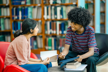 Students sharing ideas during study session in library using tablet representing teamwork learning academic preparation knowledge exchange.