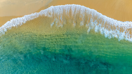 High angle drone shot showing clear blue water meeting a tropical shoreline in Huatulco, Mexico. Natural light, sharp focus, vibrant colors.