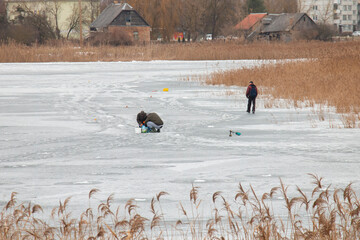 Three men walk on thin ice while winter fishing.