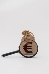 A burlap sack with a euro symbol and a magnifying glass placed beside it. The scene represents finance and currency analysis.