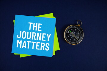 The Journey Matters text written on sticky note with compass on blue  background
