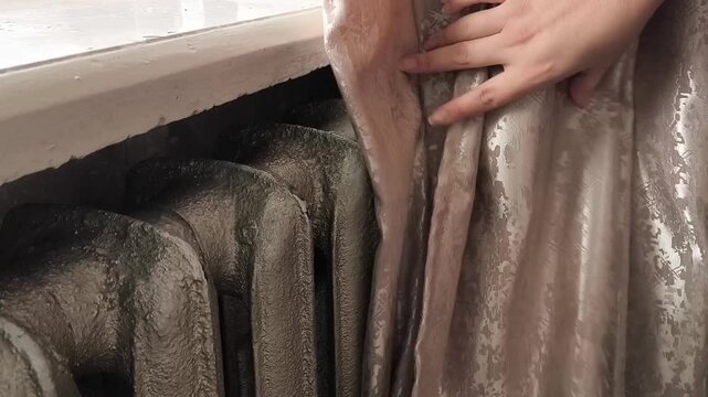 The curtains open and the old heating radiator becomes visible. Heating in the house with old radiators