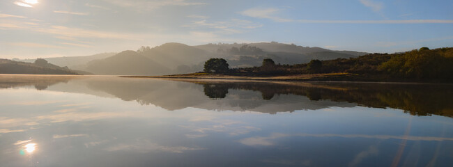 Hazy sunrise reflections over the serene waters of Stafford Lake in Novato