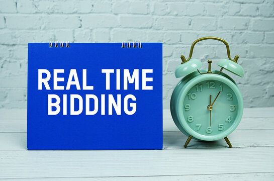 Real Time Bidding text with Mint Green Alarm Clock on wooden Background