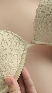 A woman shows the underwire on a beige lace bust. Women's underwear.