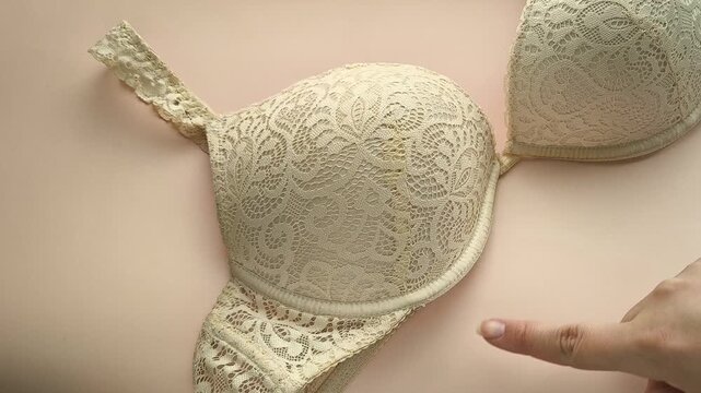 A woman shows the underwire on a beige lace bust. Women's underwear.