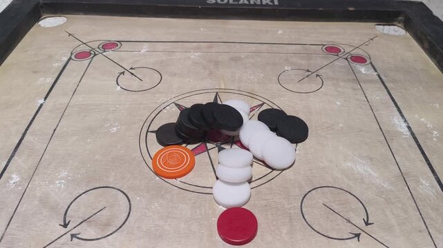 Video clip of a traditional carrom board with coins arranged at the center, symbolizing indoor games, leisure time, cultural recreation, and classic tabletop gaming in India.
