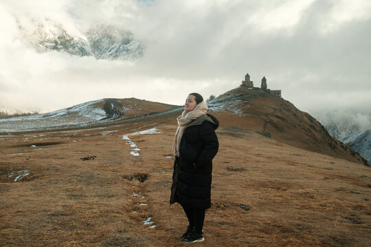 Woman in winter Coat with Gergeti Trinity Church in the Background