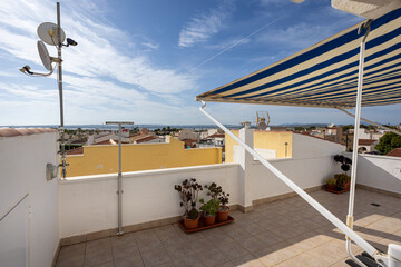 Rooftop terrace with striped awning and panoramic sea view over rooftops