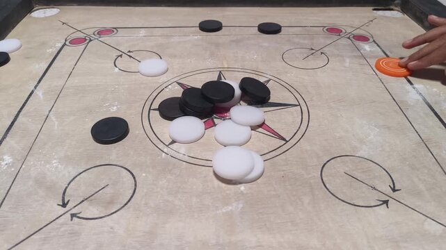Close-up of a traditional carrom board with stacked coins at the center, symbolizing indoor games, strategy, family entertainment, and classic tabletop gaming culture in India.
