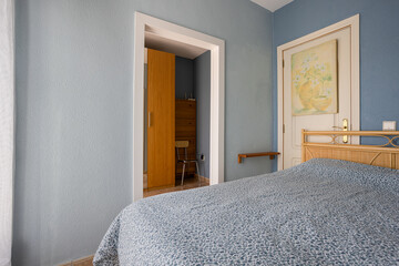 Cozy blue bedroom with rattan headboard, wardrobe view, and natural daylight