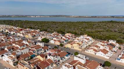 Aerial view of suburban red-roof homes near a large salt lake and green landscape