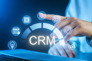 Finger pointing at CRM dashboard with icons representing various business functions and analytics at an office setting