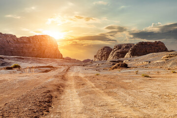 Desert road and tire tracks with spectacular yardang landforms mountain natural landscape at sunset