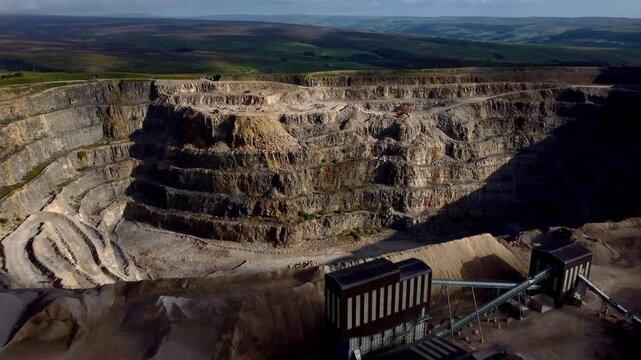 Close drone flyover of processing plant with vertical gimbal reveal of deep Yorkshire Dales limestone quarry