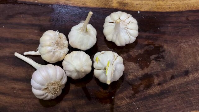raw garlic heads on dark wood surface used for healthy cooking at home
