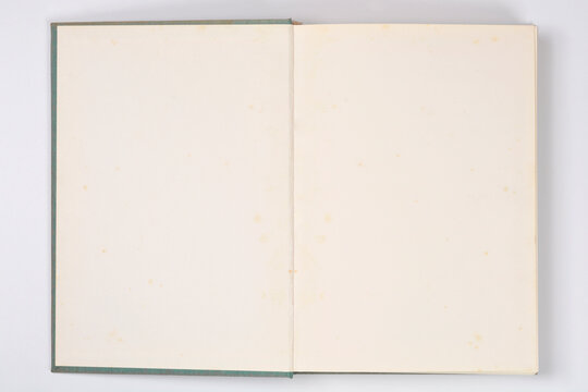 An open book lies flat against a white background, revealing two slightly yellowed, blank pages with a teal-colored cloth cover visible at the edges
