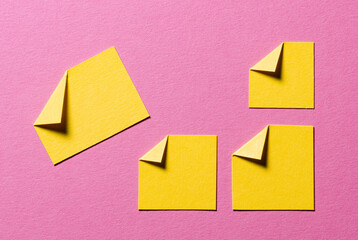 Yellow paper message notes or sheets with folded edge dog-ear earmark and copy space for text on pink background, top view flat lay conceptual desk backdrop