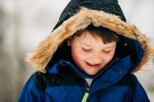 Happy child playing outdoor in falling snow