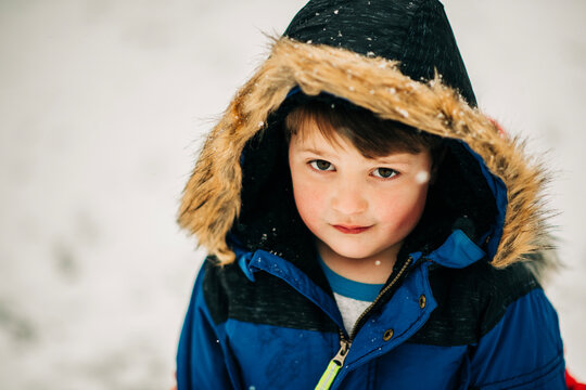 Boy in blue winter parka looking at camera