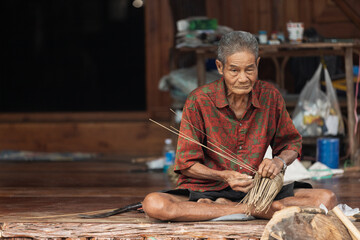 Elderly villager crafting bamboo basket on floor