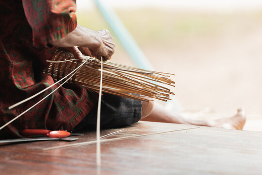 Elderly artisan weaving traditional bamboo basket in Thailand
