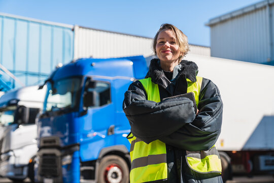 Confident woman working as a professional truck driver near semi trucks, showcasing female empowerment in transport logistics