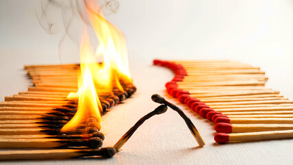 Burning matchsticks demonstrating propagation of fire and social distancing concepts in a dramatic close-up visual metaphor