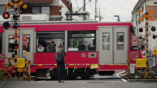 Buddhist monk waiting for a red train at a railroad crossing in tokyo