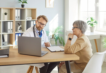 Obraz premium Doctor and senior woman sitting in medical office for consultation, looking at laptop explaining information, old patient listening attentively for healthcare, medical matters, care and communication