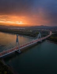 Budapest, Hungary - Aerial vertical panoramic view of the cable-stayed Megyeri Bridge over River Danube at dusk with beautiful dramatic golden sunset sky and Buda Hills at background