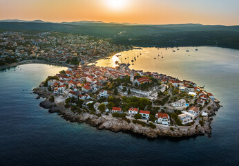 Fototapeta premium Primosten, Croatia - Aerial view of Primosten peninsula and old town on a sunny summer morning in Dalmatia, Croatia. Blue and golden sky at sunrise on the Adriatic sea coast