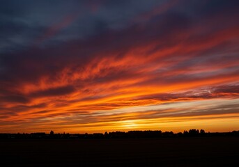 Fototapeta premium Dramatic evening sky ablaze with brilliant fiery colors reflecting across the horizon during the peaceful twilight hour ,deep ,tranquil ,dark